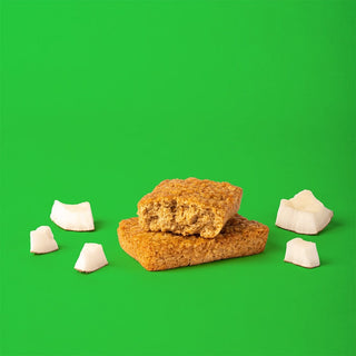 Close-up of Coconut Oat Bar surrounded by granola bars on green surface.