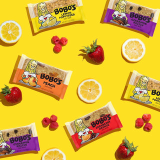 A group of food packages, a lemon cut in half, a close-up of a lemon, a strawberry, and a package of oat bar.