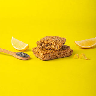 Oat bar on yellow background with surrounding lemons and poppyseeds