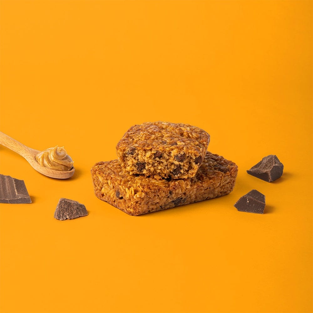Oat bar on orange background with surrounding peanut butter and chocolate chips