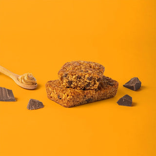 Oat bar on orange background with surrounding peanut butter and chocolate chips