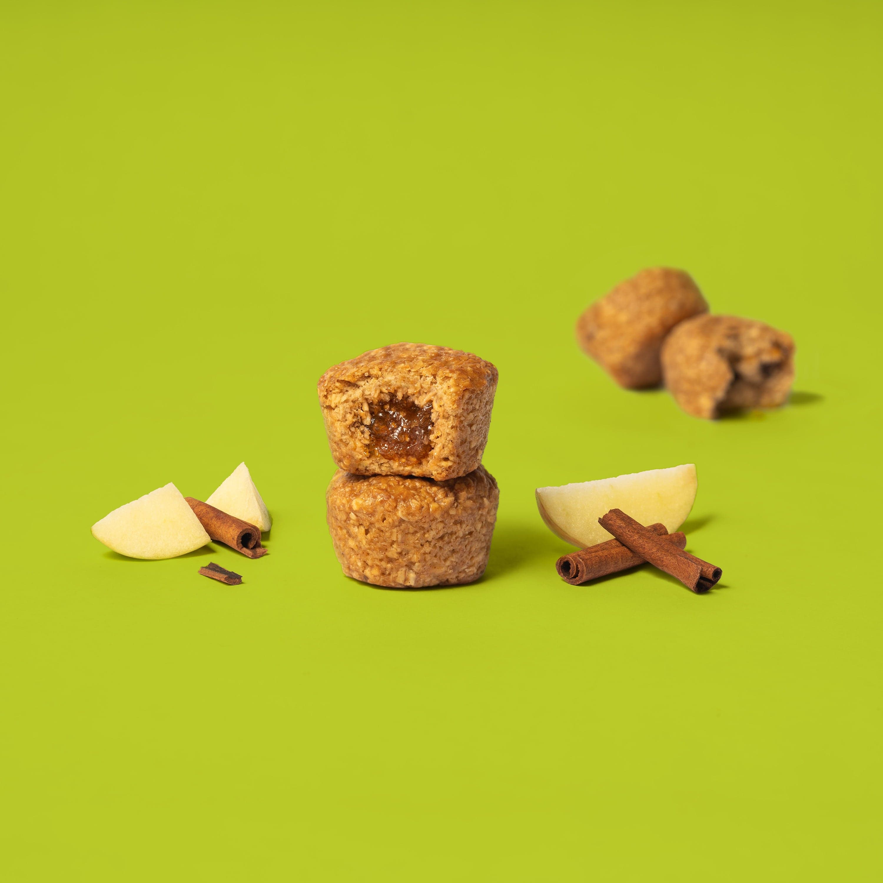 Oat bite on green background with surrounding apples and cinnamon