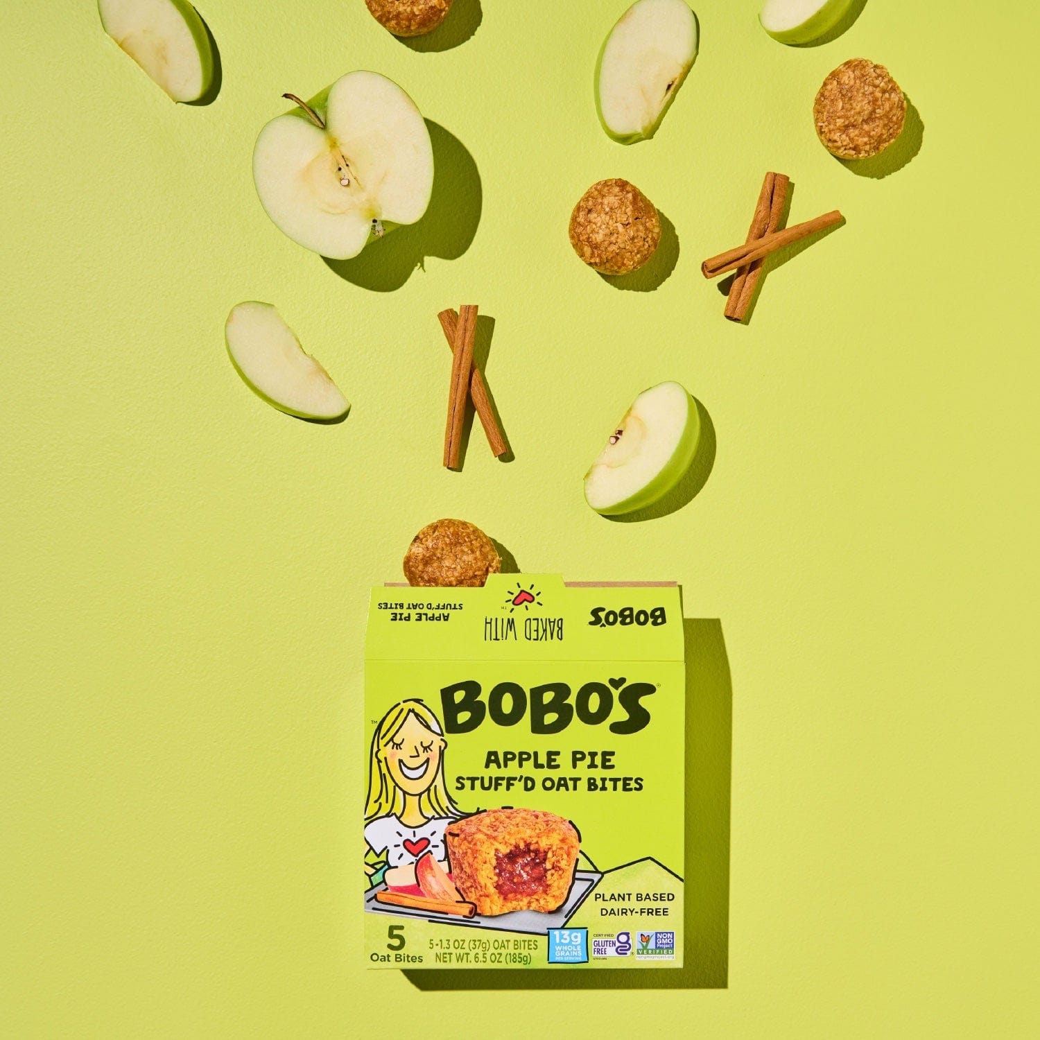 Oat bite on green background with surrounding apples and cinnamon