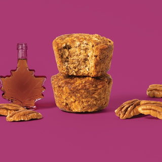 Oat bite on purple background with surrounding pecans and maple syrup