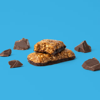 Oat bar on blue background with surrounding chocolate chunks