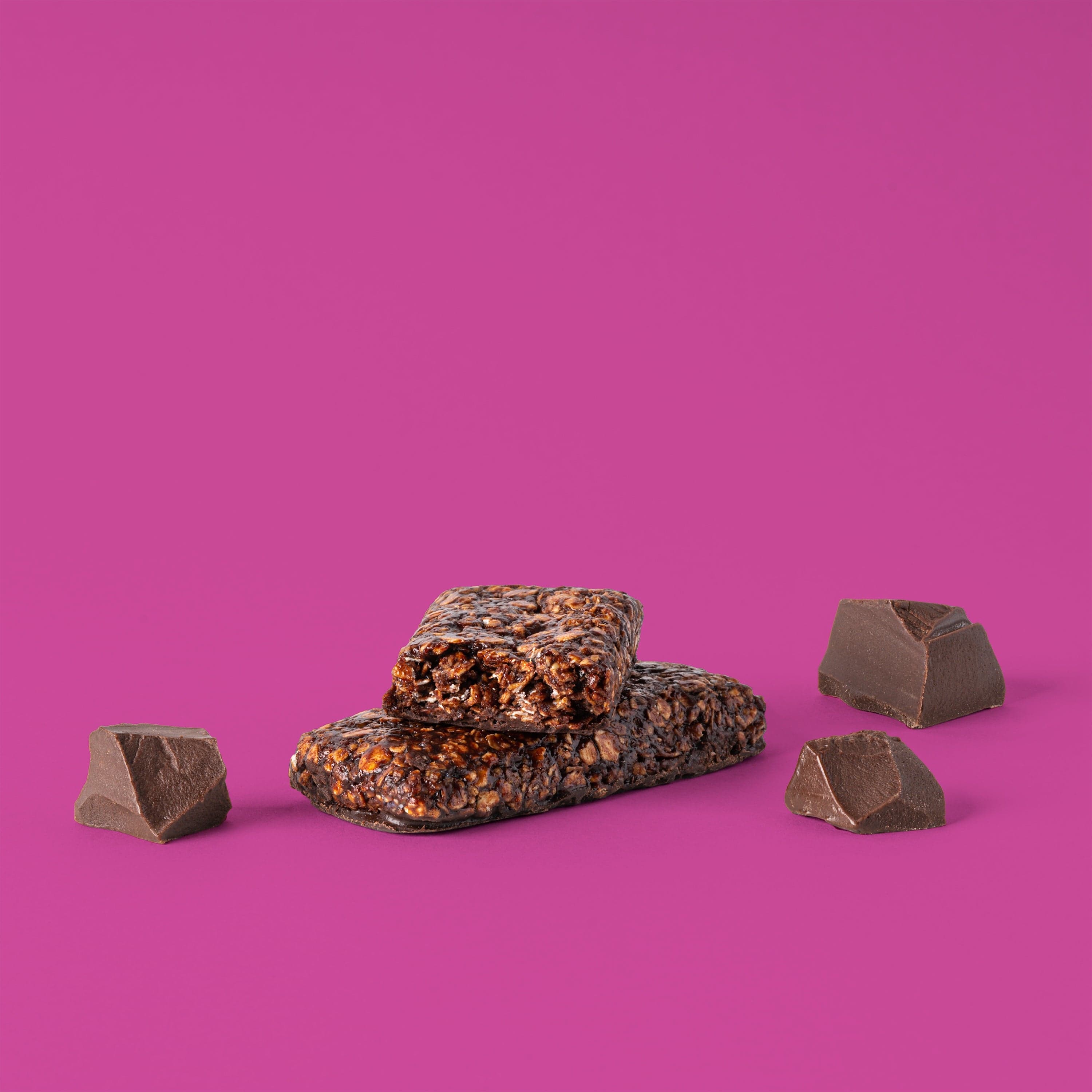 Oat bar on pink background with surrounding chocolate chunks