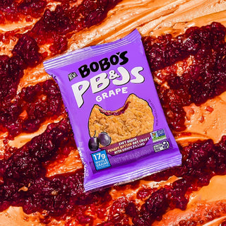 PB&J oat snack on purple background with surrounding grapes and peanut butter