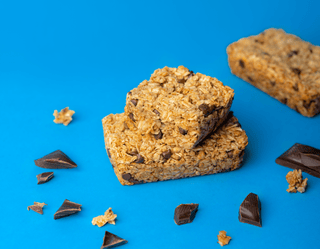 Bobo's chocolate chip bar displayed with chocolate chip chunks spread out on a blue backdrop