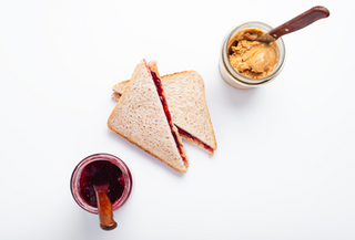 Peanut butter and jelly sandwich with jar of jelly and peanut butter