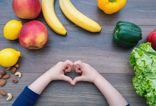 Various Fruits and Vegetables on a Table with a Child's Hands Formed in a Heart