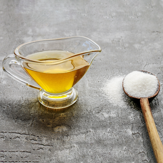 cup of honey next to a spoon full of sugar