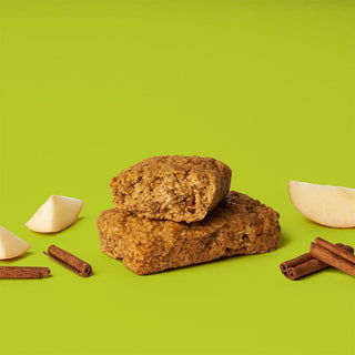Oat bar on green background with surrounding apples and cinnamon