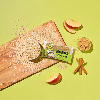 Oat bar on green background with surrounding apples and cinnamon