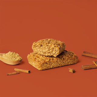Oat bar on brown background with surrounding ginger and cinnamon