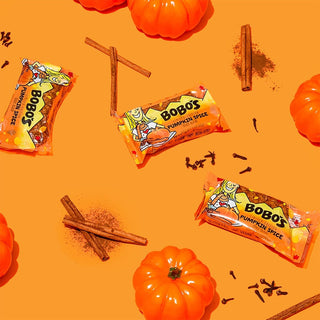 Oat bar on orange background with surrounding pumpkin chunks and cinnamon