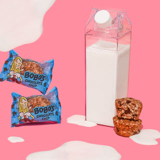 Oat bite on pink background with surrounding milk jug
