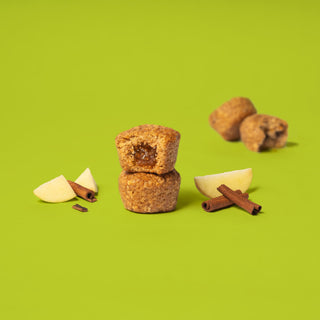 Oat bite on green background with surrounding apples and cinnamon