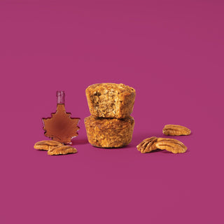 Oat bite on purple background with surrounding pecans and maple syrup
