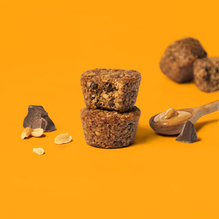 Oat bite on orange background with surrounding chocolate chips and peanut butter