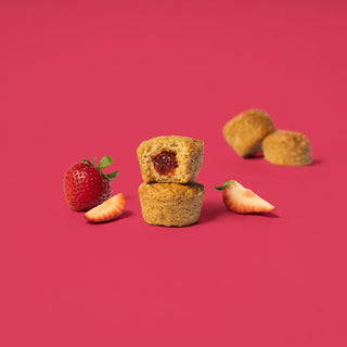 Oat bite on pink background with surrounding strawberries