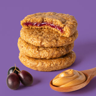 PB&J oat snack on purple background with surrounding grapes and peanut butter