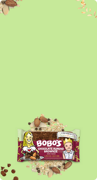 Bobo's Chocolate Almond Brownie Oat Bar displayed on a light green backdrop with oats and chocolate chips scattered